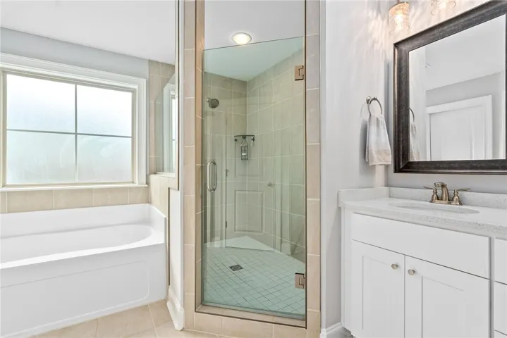 The framesless tile shower is situated bewtween the soaking tub and​​‌​​​​‌​​‌‌​‌‌​​​‌‌​‌​‌​‌​​​‌​​ vanity.