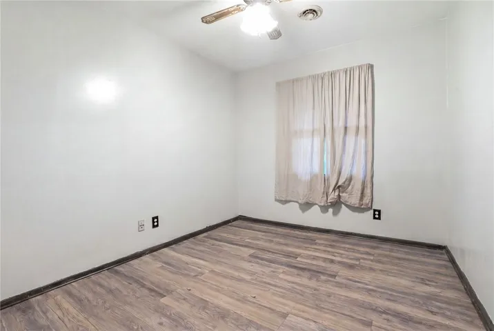 This spacious room features bright walls, a ceiling fan, and elegant wood flooring, perfect for a peaceful retreat.