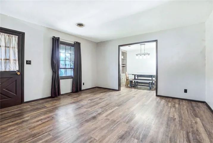This bright living area features wood flooring, leading to a dining space with built-in shelving.