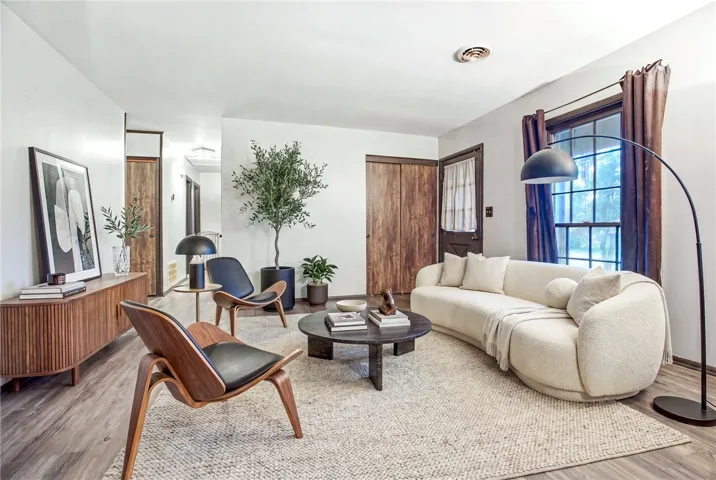 Warm wood tones and bright walls create a welcoming atmosphere in this spacious living room. (Rendering)