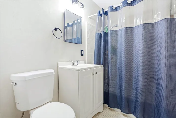 This bright bathroom features a vanity, toilet, and a practical shower area.