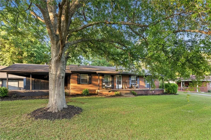 This classic brick residence features a spacious front yard and a welcoming porch, perfect for relaxation.