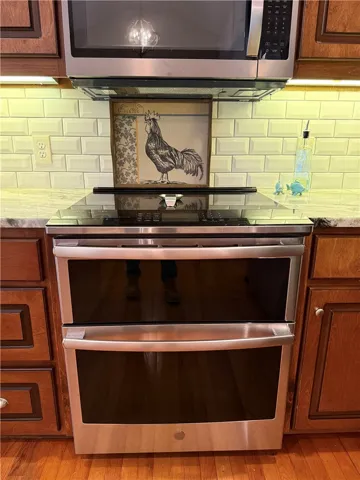 This modern kitchen features a sleek cooktop and double oven, seamlessly integrated into elegant cabinetry.