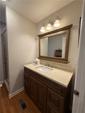 This bathroom features hardwood flooring and a stylish vanity with a single sink and elegant fixtures.