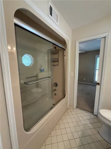 This primary bathroom features a shower with sliding glass doors and tiled flooring.