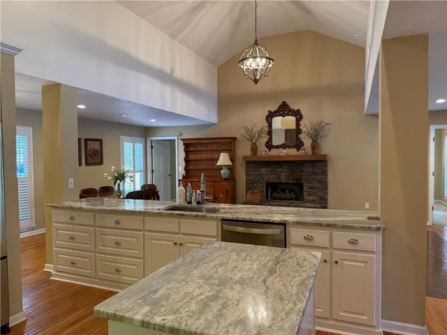 This expansive kitchen and living area features vaulted ceilings and a charming stone fireplace.
