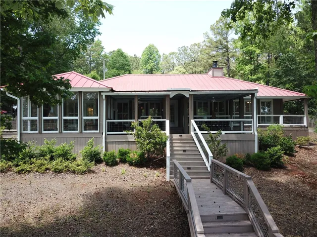 This charming home offers a welcoming facade with a serene, natural backdrop.