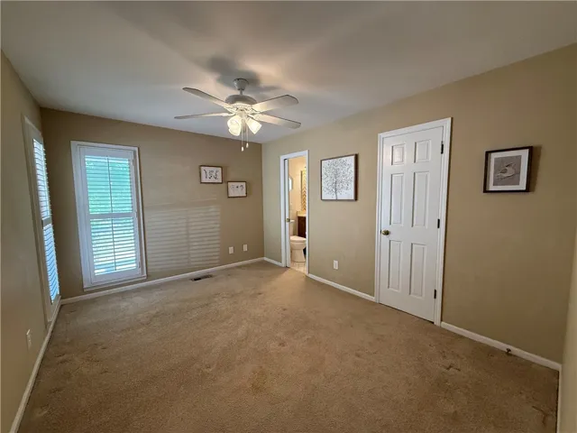 This inviting bedroom features soft carpeting and ample natural light, creating a comfortable living space.