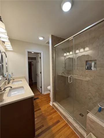 This bathroom features hardwood flooring and a spacious shower.