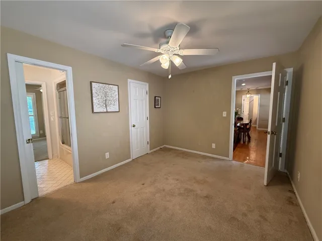 This inviting bedroom features soft carpet and a convenient ceiling fan.
