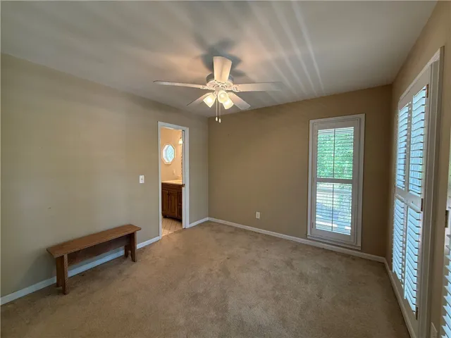 This spacious bedroom offers comfortable carpeting and a private entrance to an adjacent bathroom.