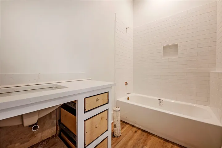 This newly constructed bathroom features a pristine vanity, spacious tub, and elegant tile work.