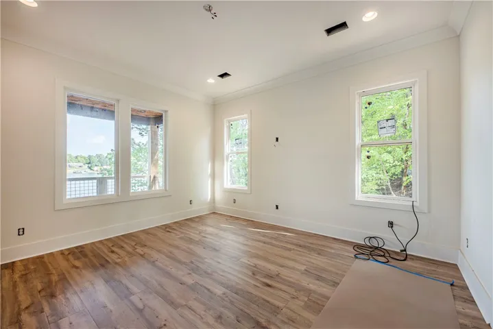 This bright room features a serene lake view through expansive windows and elegant hardwood flooring.