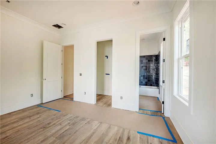 This spacious room features ample natural light and durable flooring, with a pristine adjacent bathroom.