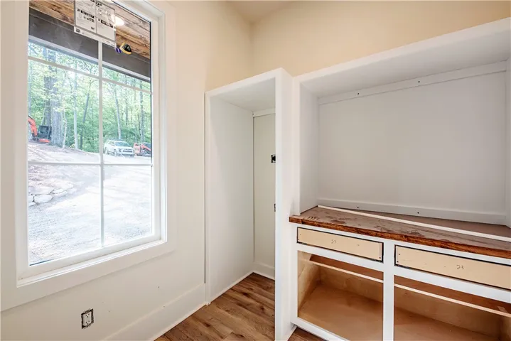 This interior space features beautiful wood flooring and built-in storage with a view of the surrounding trees.