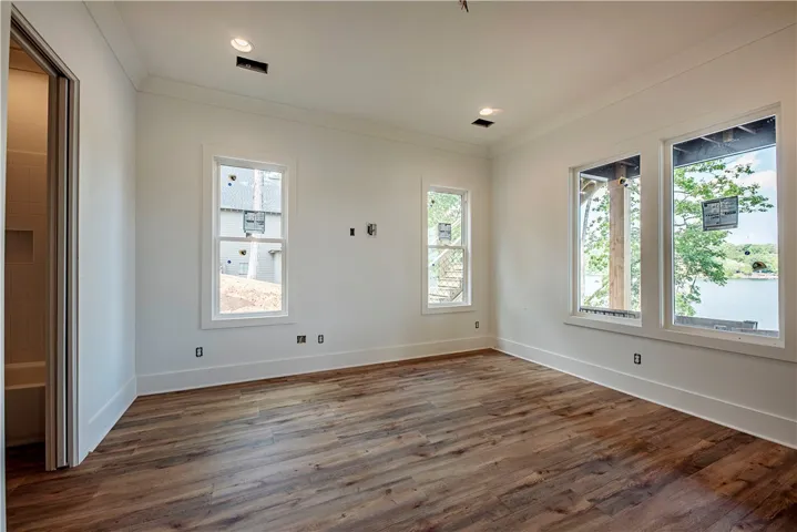 This spacious room features ample natural light, a neutral palette, and beautiful wood flooring.