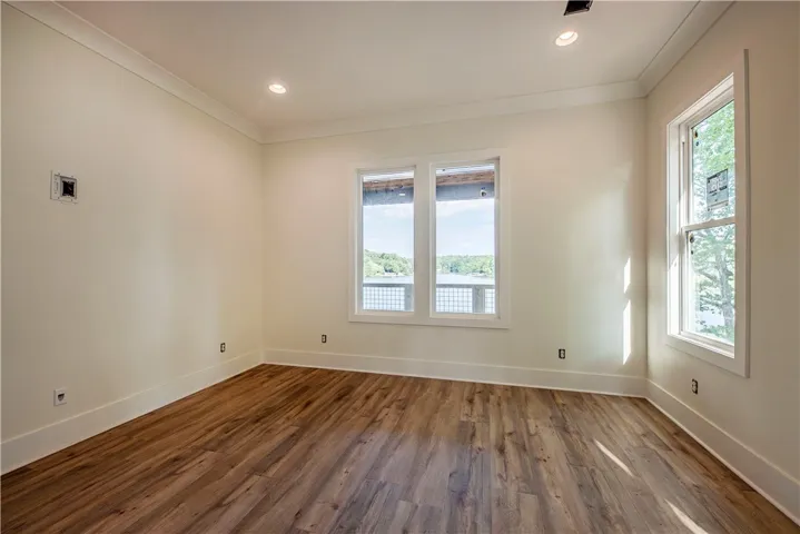 This bright room features a lake view and rich wood flooring, perfect for serene living.
