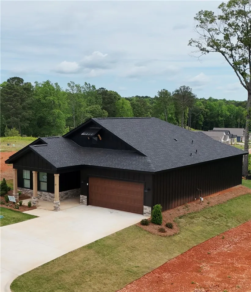 This modern residence showcases a striking dark facade with stone accents and a welcoming covered entrance.