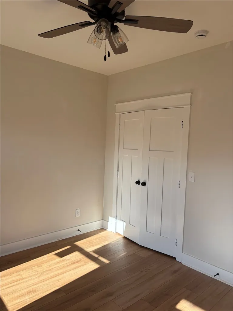 This bright room features durable laminate flooring, a closet, and a ceiling fan for optimal comfort.
