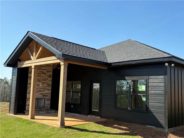 This newly constructed home features a stone fireplace, sleek dark siding, and a covered patio.