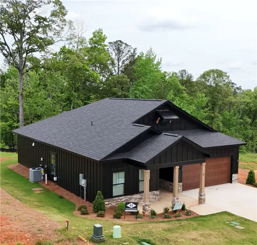 This modern home features a striking dark exterior and a well-manicured lawn, offering a serene living experience.