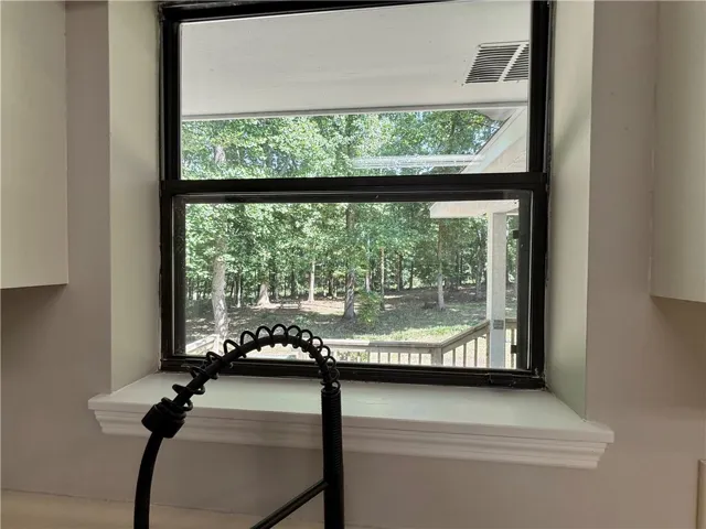 The kitchen window offers tranquil views of lush greenery, seamlessly connecting indoor comfort with nature's beauty.