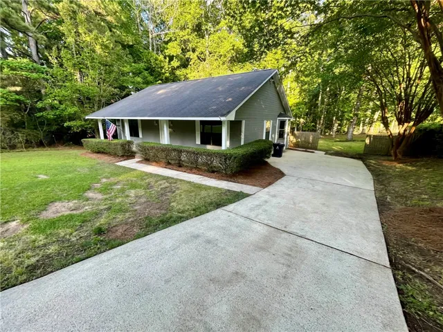 A charming cottage-style home with a welcoming front porch and lush surroundings awaits.