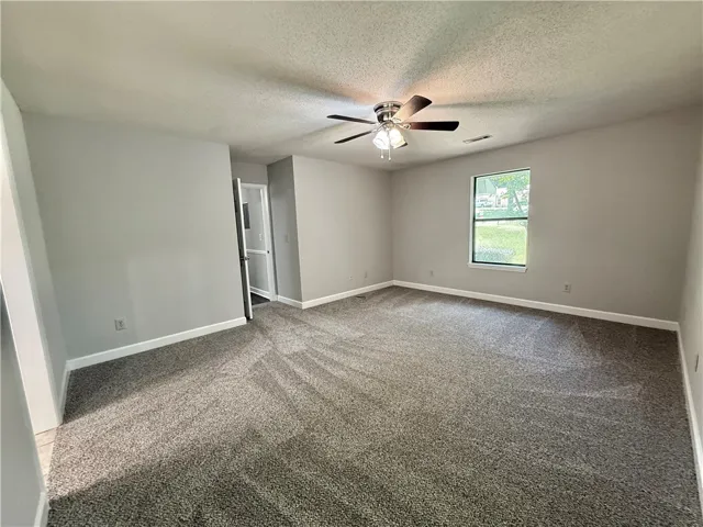 This spacious primary bedroom offers ample comfort and a pleasant view.