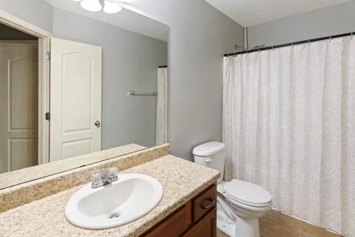 This bathroom features a functional vanity with a large mirror and practical shower area.