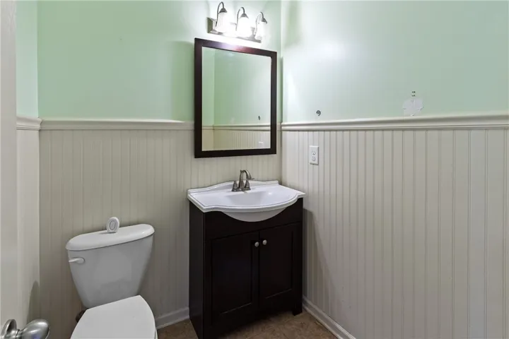 This bright bathroom features wainscoting and a functional vanity, creating a refreshing and practical space.