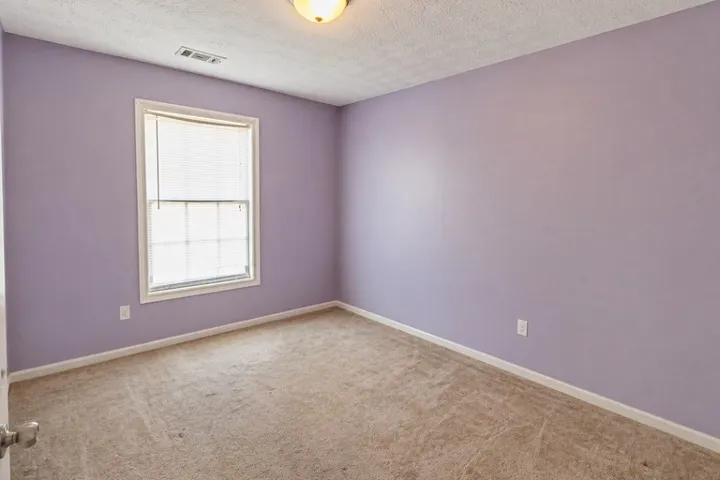 This cozy bedroom offers a tranquil retreat with soft carpet and a sunlit window.
