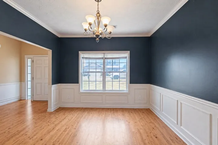 This versatile room features warm hardwood flooring, crown molding, and wainscoting, creating an inviting atmosphere.