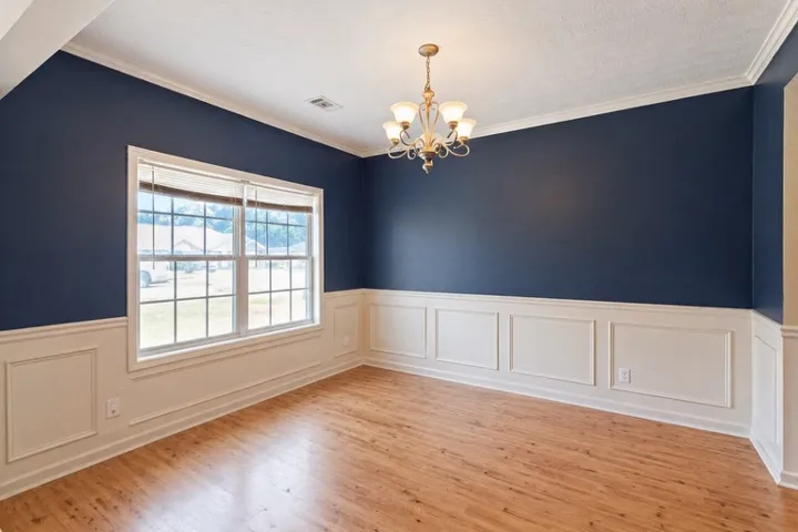 This versatile room features warm flooring and elegant wainscoting, creating an inviting atmosphere.