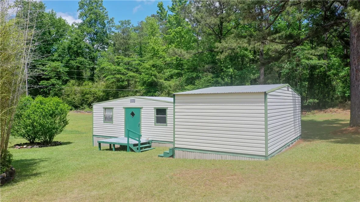 This property features three outbuildings, providing excellent storage or workshop potential amid lush greenery.