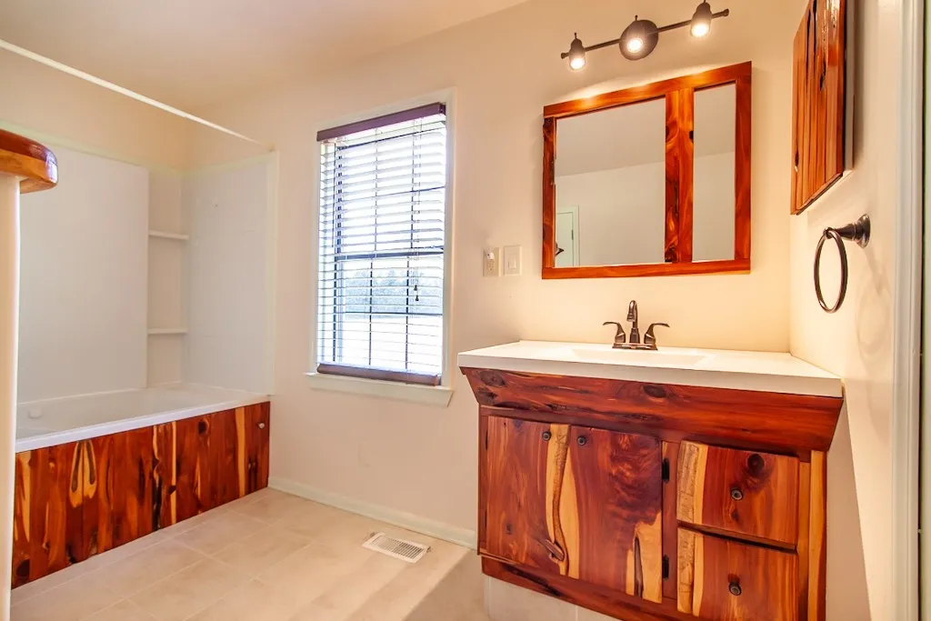 Bathroom 2 has unique wooden cabinetry, a jetted bathtub, and a window for natural light.