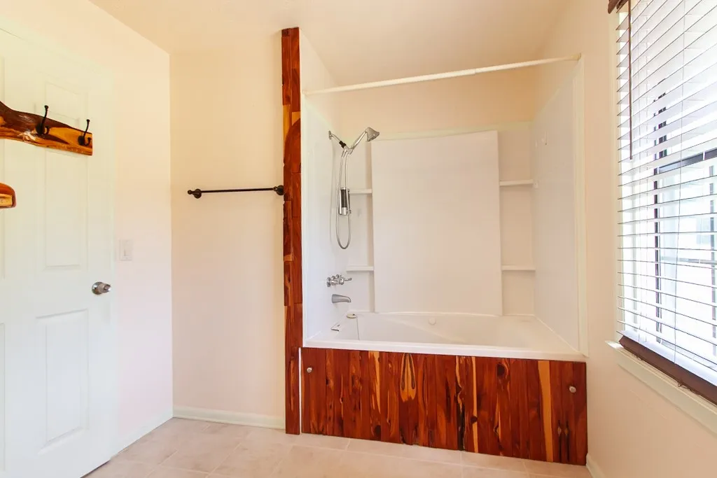 Bathroom 2 with a spacious jetted tub and shower combination with stylish wood accents.