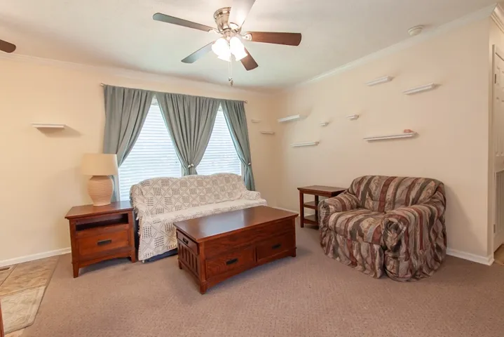 The mobile home living room is furnished and has crown molding and a ceiling fan.