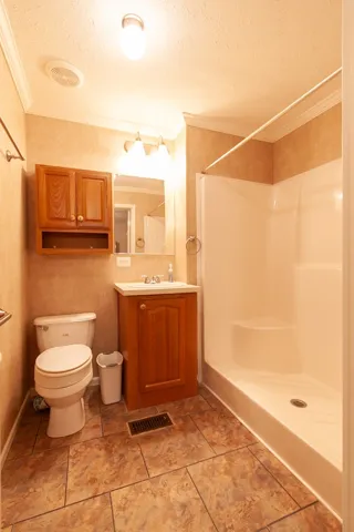 Mobile home en-suite bathroom features crown molding and a practical shower for daily routines.