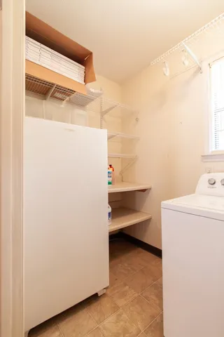 Laundry room featuring convenient shelving. Upright freezer conveys.