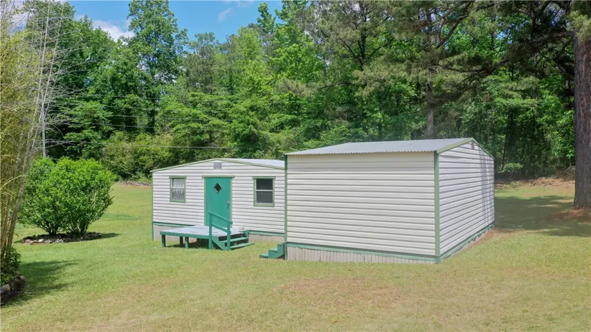 This property features three outbuildings, providing excellent storage or workshop potential amid lush greenery.