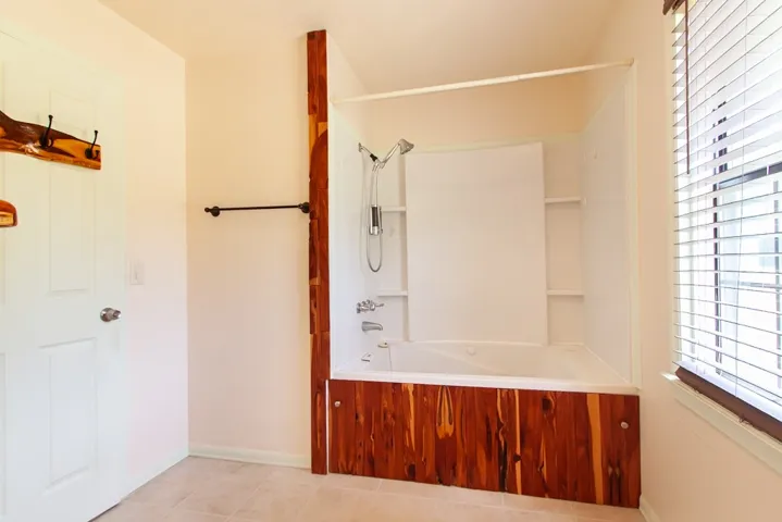 Bathroom 2 features a spacious jetted tub and shower combination with stylish wood accents.