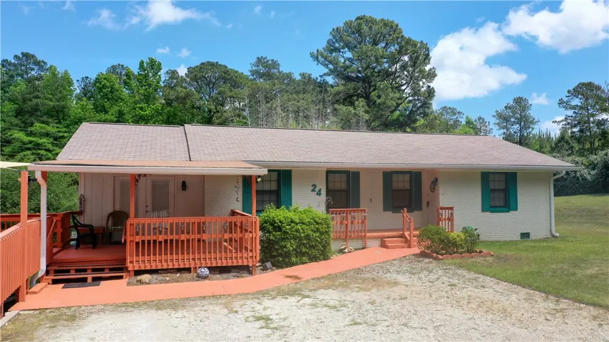 This charming home offers a spacious porch and ample natural light, surrounded by a verdant landscape.