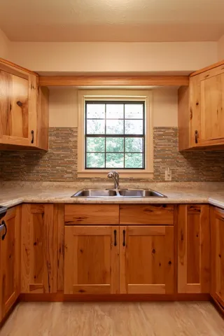 This bright kitchen features custom hickory cabinetry and a functional double sink, perfect for daily living.