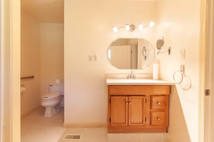 This bright en-suite bathroom features a spacious vanity with ample storage, offering comfort and convenience.