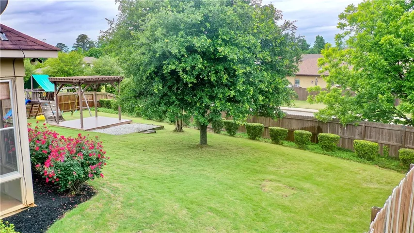 This spacious yard features lush green grass, a beautiful pergola, and ample privacy for outdoor enjoyment.