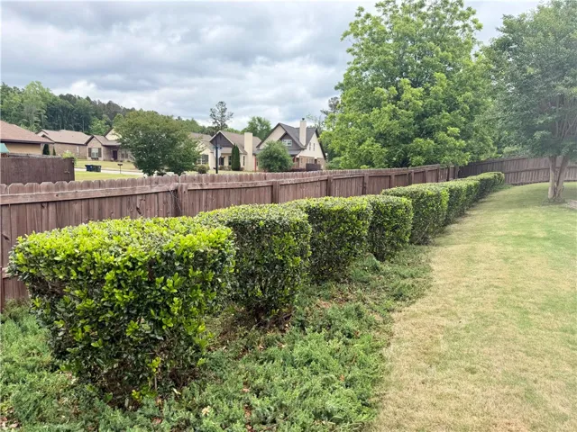 This tranquil yard features manicured shrubs and a sturdy fence, offering a perfect private outdoor retreat.