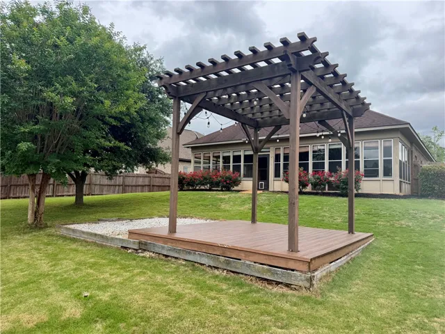 This private yard features a charming pergola with a raised wooden deck, perfect for outdoor enjoyment.