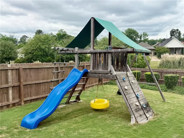 This spacious backyard features a playful swing set, perfect for outdoor recreation and relaxation.