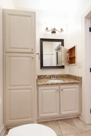 This bathroom features elegant cabinetry and a practical vanity with a modern sink and mirrored medicine cabinet.