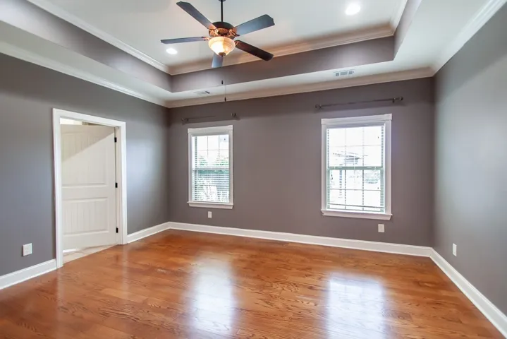 The primary bedroom also features a tray ceiling and wood flooring.